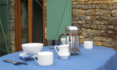 A picture of a cafetiere and coffee cups on a table on the balcony that overlooks the garden